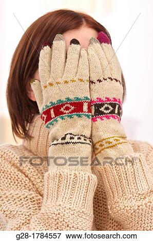 Stock Photo - Young beautiful woman in winter woolen gloves, hiding her face. Fotosearch