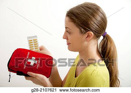 Young beautiful woman in yellow, holding a red first aid kit, and a blister of yellow tablets in her hand View Large Photo Image Stock Image - Young beautiful woman in yellow, holding a red first aid kit, and a blister of yellow tablets in her hand. Fotosearch