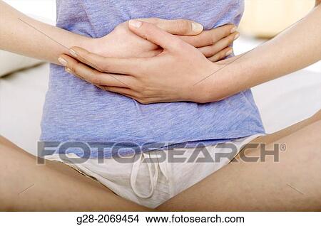 Young Beautiful Woman Sitting On A Bed And Holding Her Stomach For Pain Picture G28 2069454 Fotosearch fotosearch