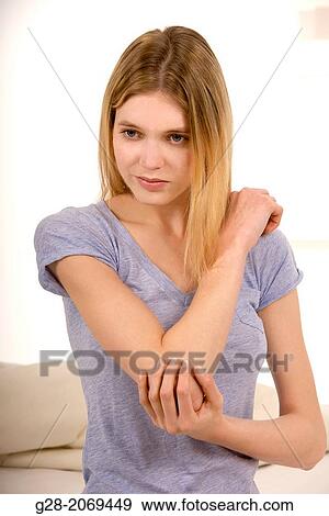 Young beautiful woman sitting on a bed and holding her stiff painful elbow View Large Photo Image Stock Photo - Young beautiful woman sitting on a bed and holding her stiff painful elbow. Fotosearch