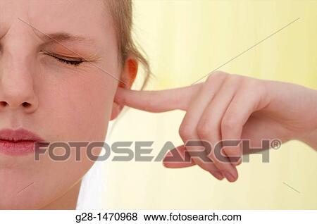 Young beautiful woman suffering from an excess of noise and stopping it by putting her finger in her ear View Large Photo Image Stock Photo - Young beautiful woman suffering from an excess of noise and stopping it by putting her finger in her ear. Fotosearch