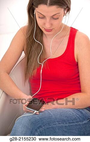 Young beautiful woman using her phone as an I pod and listening to music in a white leather armchair View Large Photo Image Stock Image - Young beautiful woman using her phone as an I pod and listening to music in a white leather armchair. Fotosearch