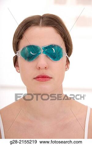 Young beautiful woman wearing a hot and cold blue mask over her eyes for headache View Large Photo Image Stock Photo - Young beautiful woman wearing a hot and cold blue mask over her eyes for headache. Fotosearch