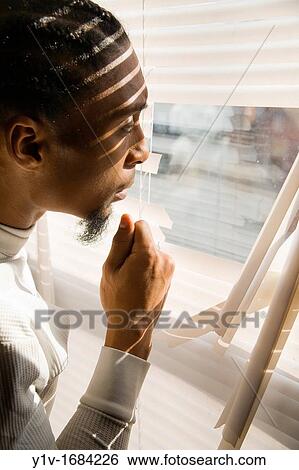Young black man looking out a window with broken blinds View Large Photo Image Stock Photograph - Young black man looking out a window with broken blinds. Fotosearch