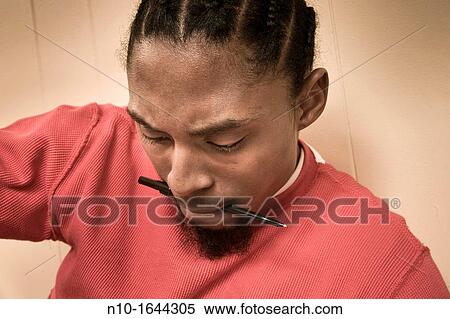Young black man with a pen in his mouth View Large Photo Image Stock Photography - Young black man with a pen in his mouth. Fotosearch