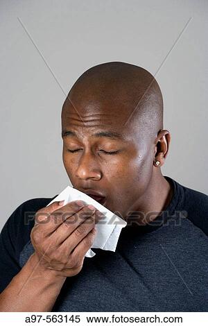 Young black man with shaved head sneezing into a tissue. View Large Photo Image Stock Photography - Young black man with shaved head sneezing into a tissue.. Fotosearch