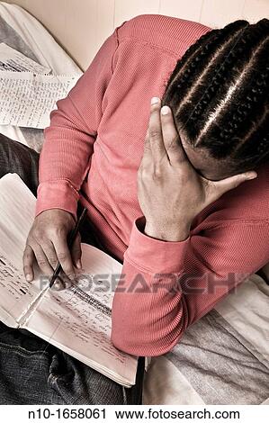 Stock Image - Young black man writing in his notebook. Fotosearch