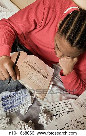 Young black man writing in his notebook View Large Photo Image Stock Image - Young black man writing in his notebook. Fotosearch