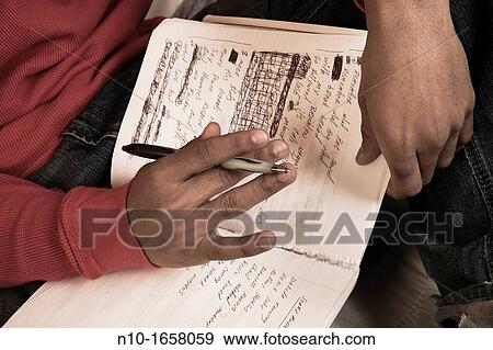 Young black man writing in his notebook View Large Photo Image Stock Photo - Young black man writing in his notebook. Fotosearch