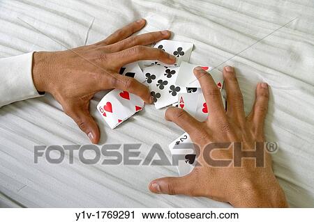 Stock Image - Young black man's hands with torn and crumpled playing cards. Fotosearch