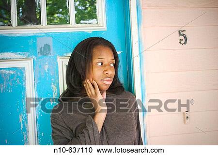 Stock Image - Young black woman posing in front of her house.. Fotosearch
