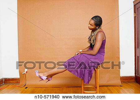 Young black woman sitting on a stool, holding up her feet View Large Photo Image Stock Image - Young black woman sitting on a stool, holding up her feet. Fotosearch