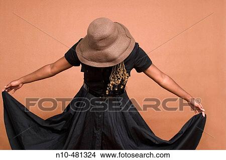 Young black woman, wearing a hat, holding up the corners of her dress View Large Photo Image Picture - Young black woman, wearing a hat, holding up the corners of her dress. Fotosearch