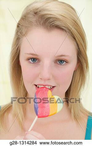 Young blond attractive woman with long hair holding a multi colored lollipop and smiling View Large Photo Image Picture - Young blond attractive woman with long hair holding a multi colored lollipop and smiling. Fotosearch
