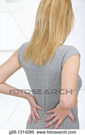 Young blond attractive woman with long hair holding her back for pain View Large Photo Image Stock Photo - Young blond attractive woman with long hair holding her back for pain. Fotosearch