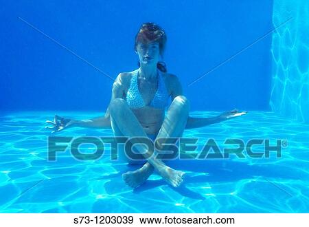 Stock Photo - Young blond woman doing yoga underwater in a swimming pool. Fotosearch