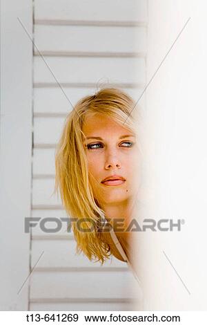 Stock Photo - Young blond woman hiding behind wall. Fotosearch