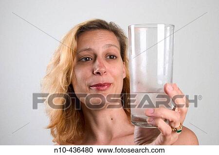 Young blond woman looking at a glass of water that she is holding in her hand. View Large Photo Image Stock Image - Young blond woman looking at a glass of water that she is holding in her hand.. Fotosearch