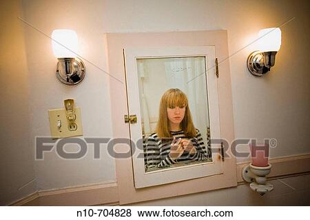 Young blond woman looking at herself in the bathroom mirror. View Large Photo Image Stock Photo - Young blond woman looking at herself in the bathroom mirror.. Fotosearch