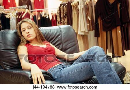 Young blond woman sitting on a sofa in clothing store View Large Photo Image Stock Photo - Young blond woman sitting on a sofa in clothing store. Fotosearch