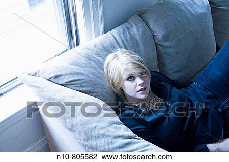 Young blond woman sitting on her living room sofa. View Large Photo Image Stock Image - Young blond woman sitting on her living room sofa.. Fotosearch