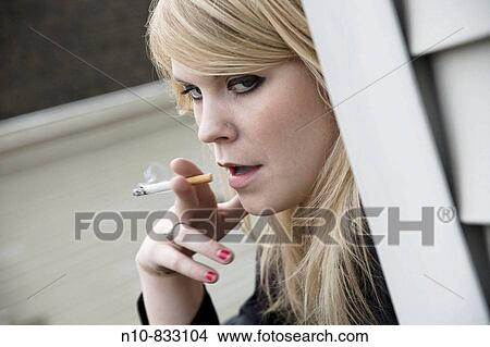 Young blond woman smoking a cigarette. View Large Photo Image Picture - Young blond woman smoking a cigarette.. Fotosearch