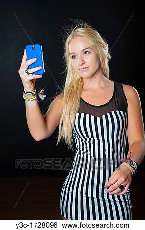 Young blond woman taking a picture of herself with a mobile phone View Large Photo Image Stock Photograph - Young blond woman taking a picture of herself with a mobile phone. Fotosearch