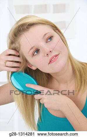 Young blond woman with long hair brushing her hair with a turquoise blue hair brush View Large Photo Image Stock Image - Young blond woman with long hair brushing her hair with a turquoise blue hair brush. Fotosearch