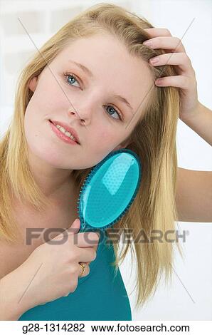 Young blond woman with long hair brushing her hair with a turquoise blue hair brush View Large Photo Image Stock Image - Young blond woman with long hair brushing her hair with a turquoise blue hair brush. Fotosearch