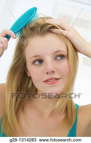Young blond woman with long hair brushing her hair with a turquoise blue hair brush View Large Photo Image Stock Image - Young blond woman with long hair brushing her hair with a turquoise blue hair brush. Fotosearch
