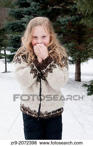 Young blonde girl dressed in a woolen sweater hugs self to keep warm outdoors on a winter day. View Large Photo Image Stock Photo - Young blonde girl dressed in a woolen sweater hugs self to keep warm outdoors on a winter day.. Fotosearch