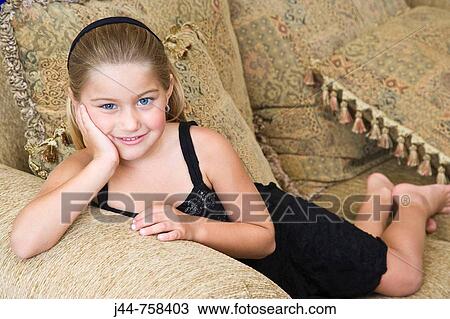 Young blonde girl laying on a sofa, smiling, portrait View Large Photo Image Stock Image - Young blonde girl laying on a sofa, smiling, portrait. Fotosearch