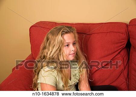 Young blonde girl sitting on her sofa View Large Photo Image Stock Photo - Young blonde girl sitting on her sofa. Fotosearch