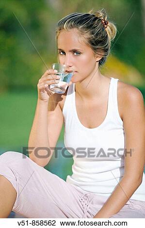 Stock Image - Young blonde woman drinking water. Fotosearch