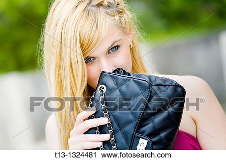 Young blonde woman feeling guilty, hiding behind her purse View Large Photo Image Stock Image - Young blonde woman feeling guilty, hiding behind her purse. Fotosearch
