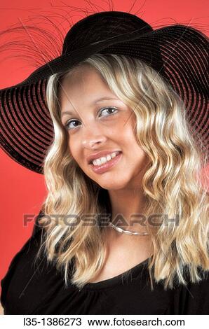 Young blonde woman in a black hat against a red background View Large Photo Image Stock Image - Young blonde woman in a black hat against a red background. Fotosearch