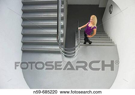 Stock Image - Young blonde woman on stairs. Fotosearch
