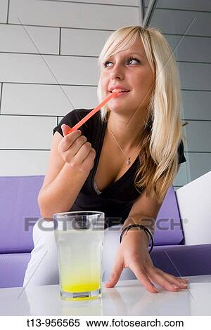 Young blonde woman with a glass of an unstirred drink View Large Photo Image Stock Photography - Young blonde woman with a glass of an unstirred drink. Fotosearch