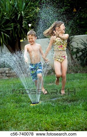 Young boy and girl running through a yard sprinkler View Large Photo Image Stock Photo - Young boy and girl running through a yard sprinkler. Fotosearch