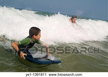 Young boy and his mother surfing waves together at Le Porge beach, Bordeaux, France View Large Photo Image Stock Image - Young boy and his mother surfing waves together at Le Porge beach, Bordeaux, France. Fotosearch