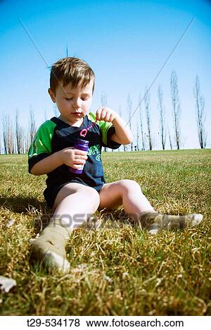 Young boy blowing bubbles in the park View Large Photo Image Stock Photo - Young boy blowing bubbles in the park. Fotosearch