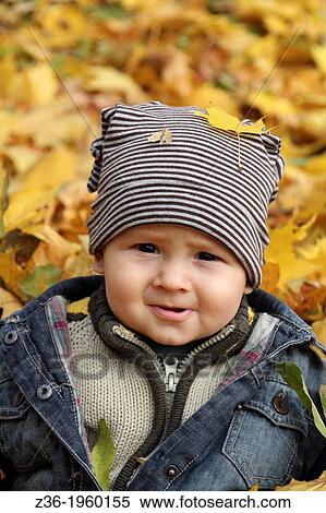 Stock Photography - Young boy covered with autumn leaves.. Fotosearch