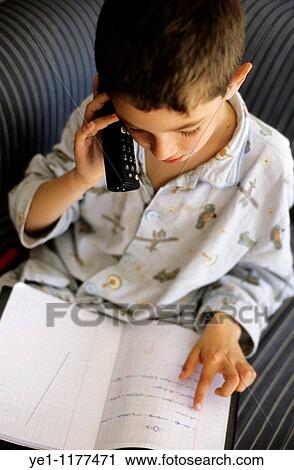 Stock Image - Young boy discussing his homework with a friend on the phone.. Fotosearch