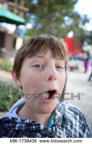 Stock Photography - young boy eating with mouth open. Fotosearch