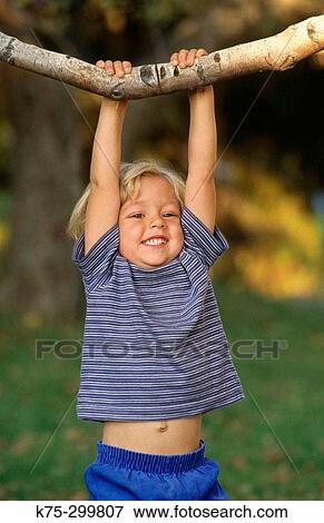 Stock Photo - young boy hanging from tree branch. Fotosearch