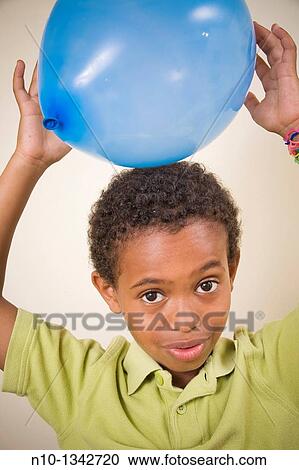 Young boy holding a balloon over his head View Large Photo Image Stock Image - Young boy holding a balloon over his head. Fotosearch