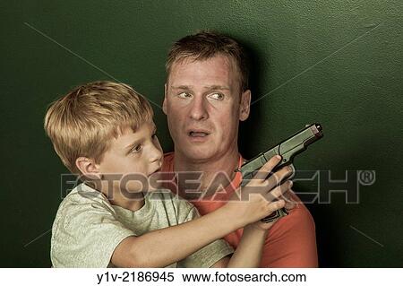 Stock Photography - Young boy, holding a toy gun, with his father.. Fotosearch