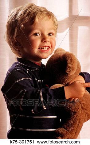 Stock Image - Young boy holding teddy bear. Fotosearch
