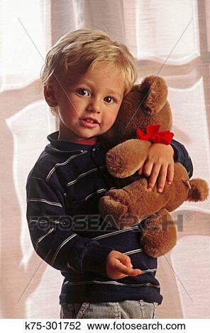 Stock Image - Young boy hugging his teddy bear. Fotosearch