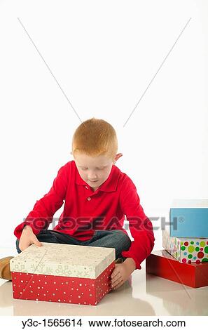 Young boy impatiently opening a gift box View Large Photo Image Picture - Young boy impatiently opening a gift box. Fotosearch